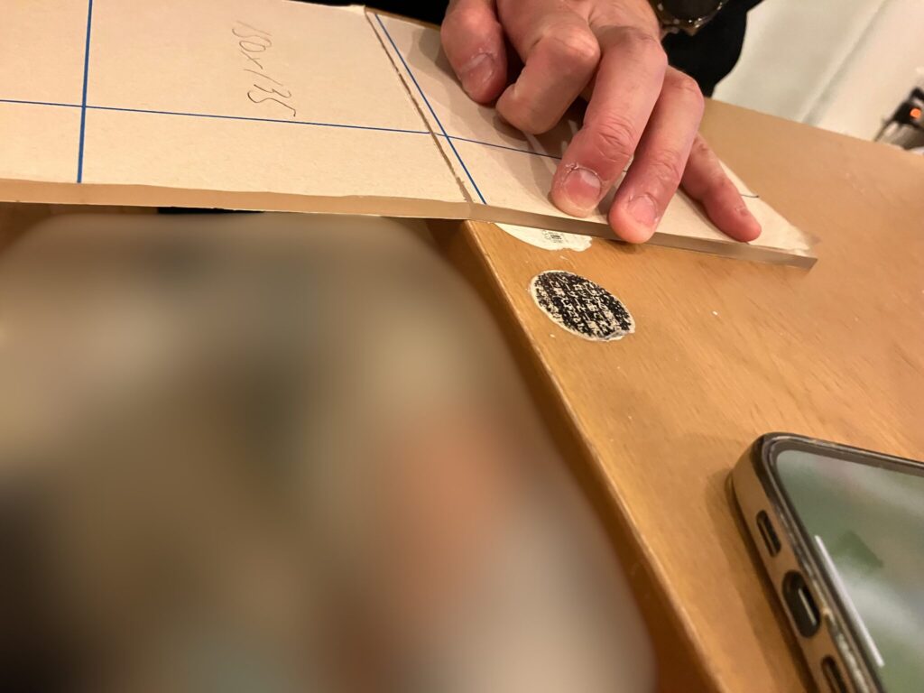 アクリル板を、カッターで入れた切れ目の部分で、机の端を使って切断しようとしている写真