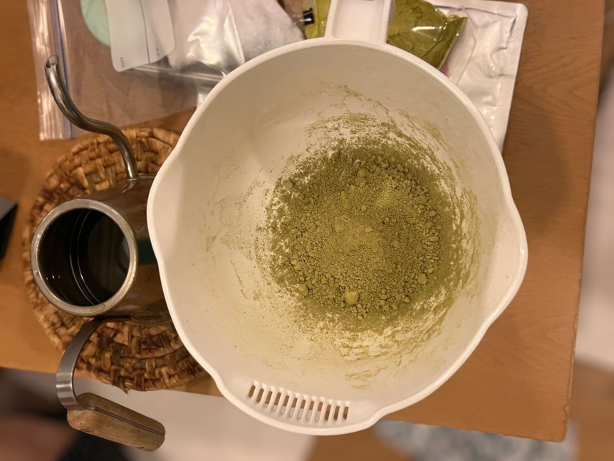 白いボールにヘナの粉を入れた写真。左にお湯の入ったやかん。