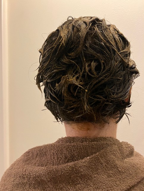 手袋をした手でヘナペーストを後頭部に直接塗布した写真。