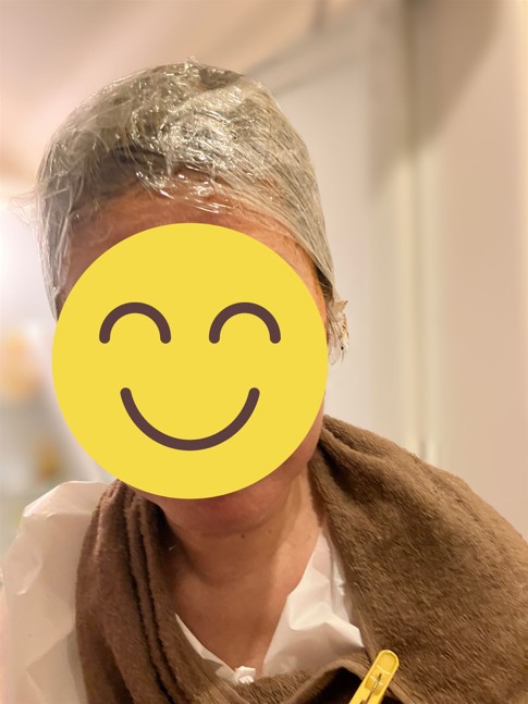 手袋をした手でヘナペーストを直接塗布した後、頭部全面にラップをまいた写真。