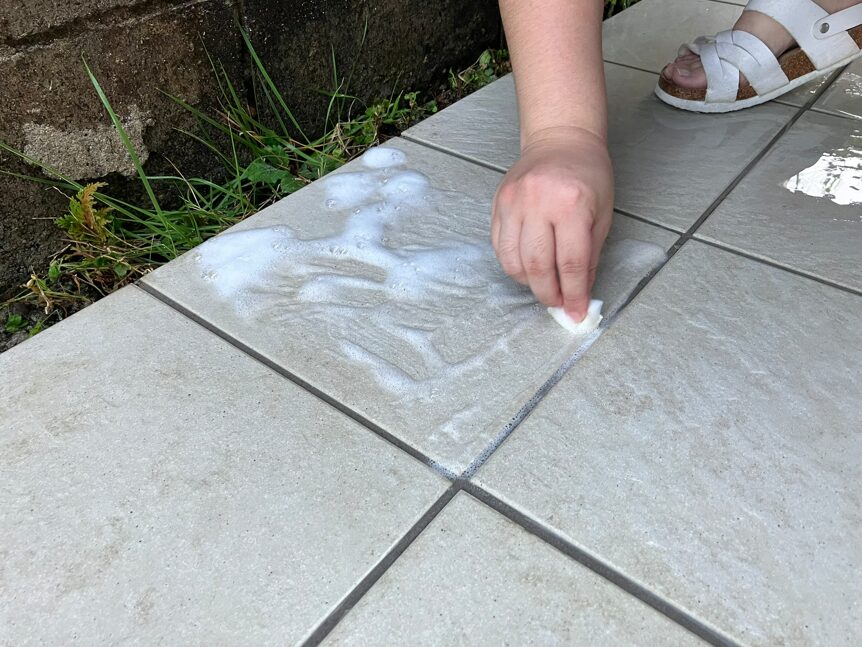 重曹とウタマロクリーナーを付けたタイルをメラミンスポンジでこすっている写真